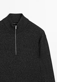 Pull-over noir à demi-zip en tissu tricoté texturé avec col haut et col côtelé. Comprend des détails de fermeture éclair en argent.