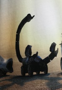 Černý robotický štír s pohyblivými nohami a ocasem, umístěný na kolech, na pozadí s gradientem. Texturovaný kovový povrch.