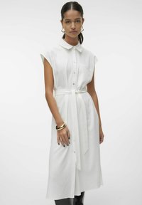 Abito camicia bianco con maniche corte, chiusura con bottoni, cintura in vita e tasca frontale. Tessuto liscio con un aspetto leggermente strutturato.