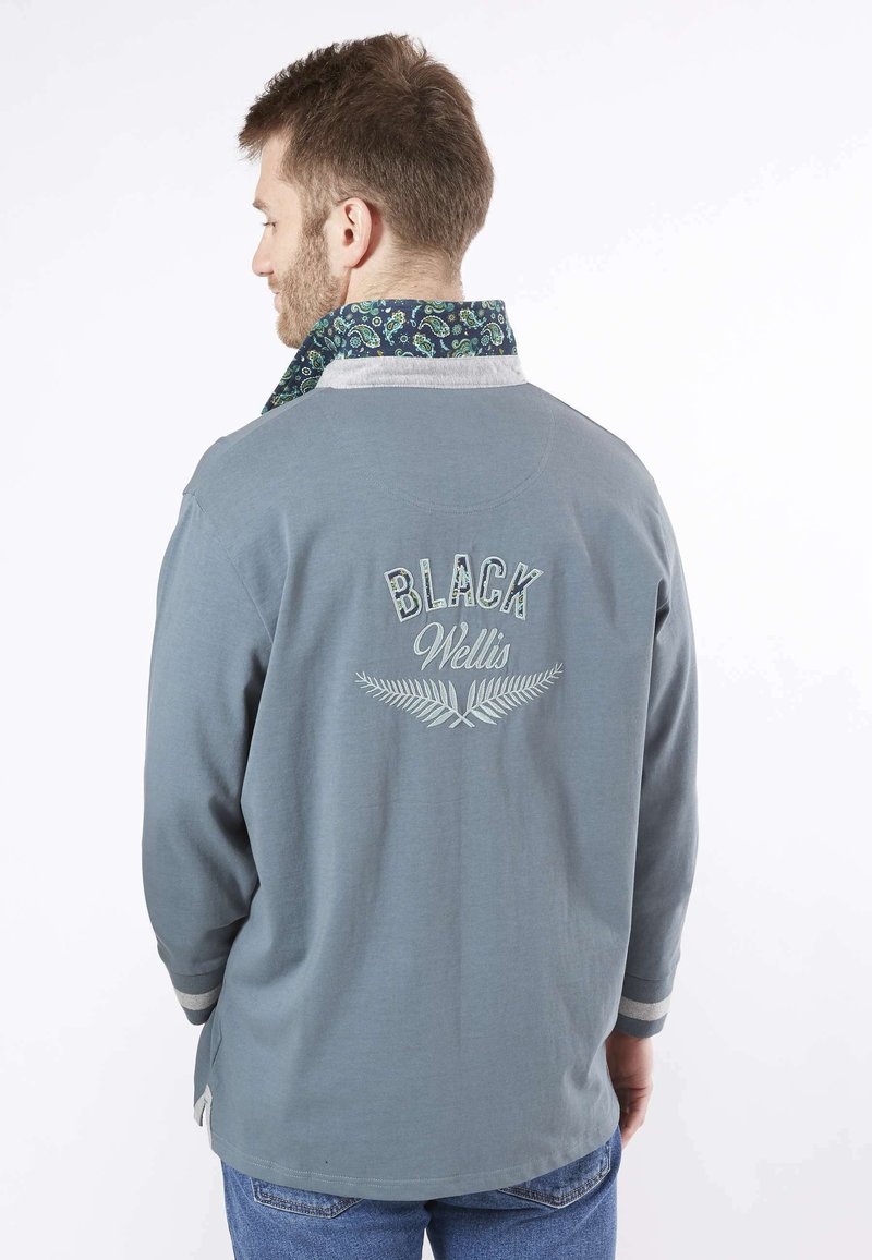 Chemise grise à manches longues avec un col à motifs, arborant les inscriptions "BLACK" et "Wellis" brodées au dos en blanc. Manches à rayures et coupe décontractée.