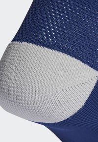 Calcetín azul con un upper texturizado que incluye una sección de malla, y un puño acanalado gris sólido en el tobillo para mayor soporte.