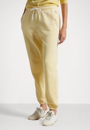 Pantalones de chándal amarillo claro con puños ajustados, cintura con cordón y bolsillos laterales. Fabricados en un tejido suave, cuentan con un pequeño logo azul en la cadera.