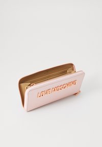 Roza usnjena denarnica z zlatim zadrgo, na sprednji strani z vtisnjenim napisom "LOVE MOSCHINO". Gladka tekstura in pravokotna oblika.