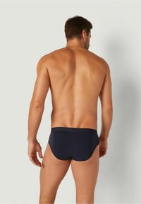 Slip da uomo blu navy con una cintura morbida e un tessuto liscio, caratterizzati da una vestibilità aderente e dettagli di cucitura minimi. Vista posteriore mostrata.