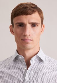 Witte button-down overhemd met een subtiel marineblauw patroon, met een gestructureerde kraag en een zachte stoftextuur. Geen opvallende accenten of kenmerken.