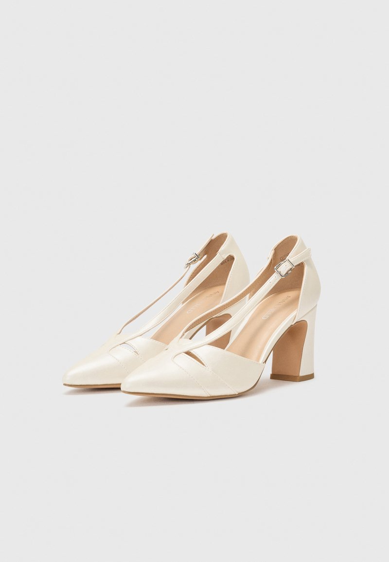 Tacchi bianchi a punta con dettaglio a taglio, cinturino alla caviglia e tacco a blocco. Realizzati in materiale liscio con una finitura opaca.