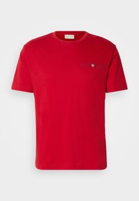 T-shirt rouge à manches courtes avec col rond, petit logo GANT et emblème de bouclier imprimés sur le côté gauche de la poitrine.