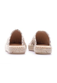 Espadrilles con parte superior tejida, espalda abierta y suela de yute trenzado. Paleta de colores naturales con un acabado texturizado y diseño plano.