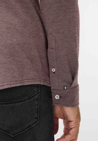 Bordeaux gekleed shirt met een visgraatpatroon, knopenmanchetten met witte knoppen en een klein meerkleurig label op de mouw.