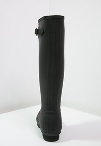 Schwarzer Gummistiefel in knielanger Form mit glatter Oberfläche, einem Schnallen-Detail an der Seite und einer strukturierten Sohle für bessere Bodenhaftung.