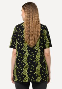 Černé tričko s potiskem jasně zelených květin. Krátké rukávy a volný střih s rovně střiženým lemem.