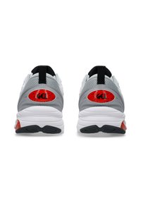 Chaussures de sport gris et blanches avec des accents rouges et une tige en maille texturée. Talon arrondi avec un élément de coussinage en gel visible.