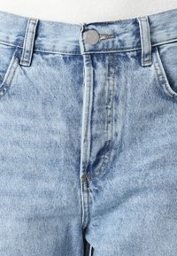 Lyseblå denimjeans med klassisk snitt, med standard knappelukking, beltestropper og subtil fading på stoffet.