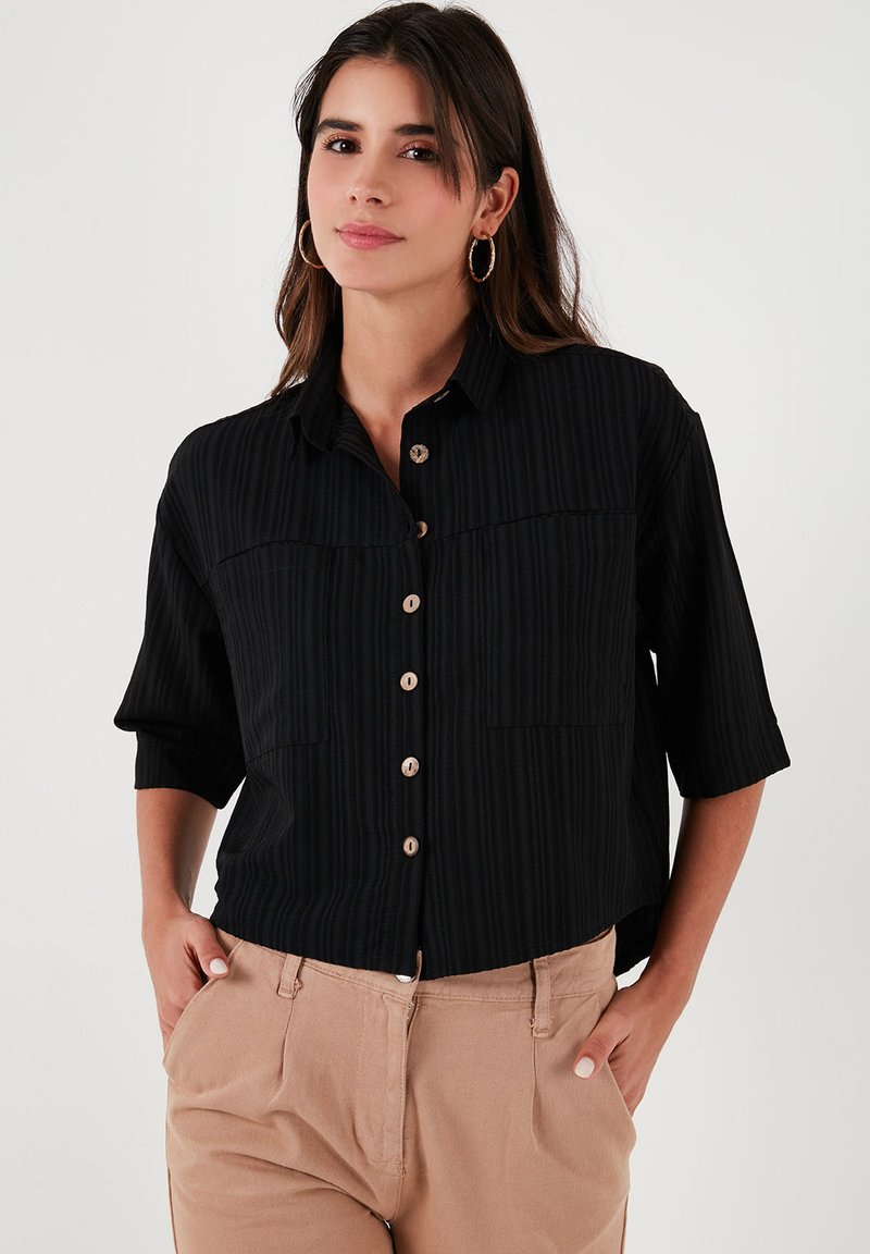 Black short-sleeve shirt with vertical stripes, button front, and two chest pockets. Features wooden buttons and a relaxed fit.