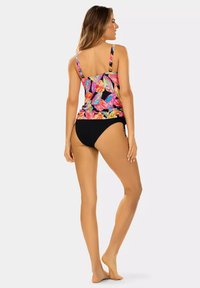 Kolorowy top tankini w kwiaty z cienkimi ramiączkami, czarne majtki kąpielowe. Jasny wzór z tropikalnymi liśćmi na ciemnym tle. Gładka tekstura.