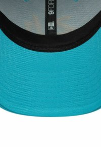 Türkisfarbene Baseballmütze mit flachem Schirm, ausgestattet mit einer schwarzen Innenseite und strukturiertem Stoff. Das Etikett zeigt "9FORTY" mit Netzfutter.