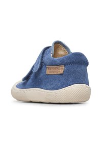 Scarpa in camoscio blu con suola in gomma beige, cinturino in velcro e superficie texturizzata. Presenta un'etichetta con il marchio sul tallone.