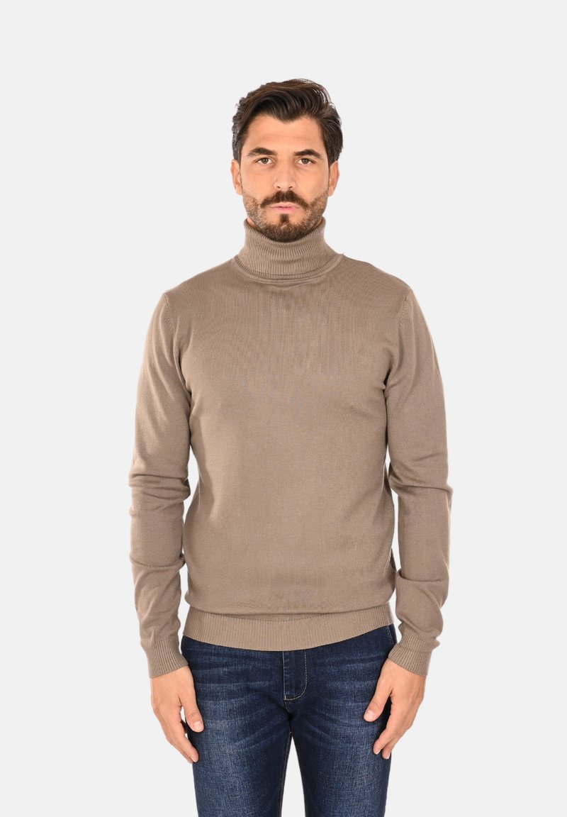 Maglione collo alto di colore marrone chiaro con texture a coste, dotato di maniche aderenti e orlo dritto, abbinato a jeans di denim scuri.