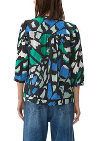 Chemise noire avec un motif abstrait coloré en vert, bleu et blanc. Présente des manches trois-quarts et une coupe décontractée.