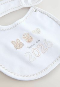 White cotton bib featuring light embroidery of a bunny, paw print, and bear, with "born in 2026" in soft pastel colors and stitched accents.