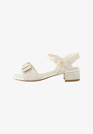 Nyitott orrú, alacsony blokk sarokkal rendelkező szandál csillogó pántokkal, bokapánttal és díszes masnival az elülső pánton, világos bézs árnyalatokban.