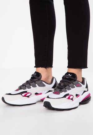 Adidași sportivi cu un amestec de materiale albe, gri și roz. Formă largă, cu plasă texturată, talpă cu amortizare și închidere cu șiret.