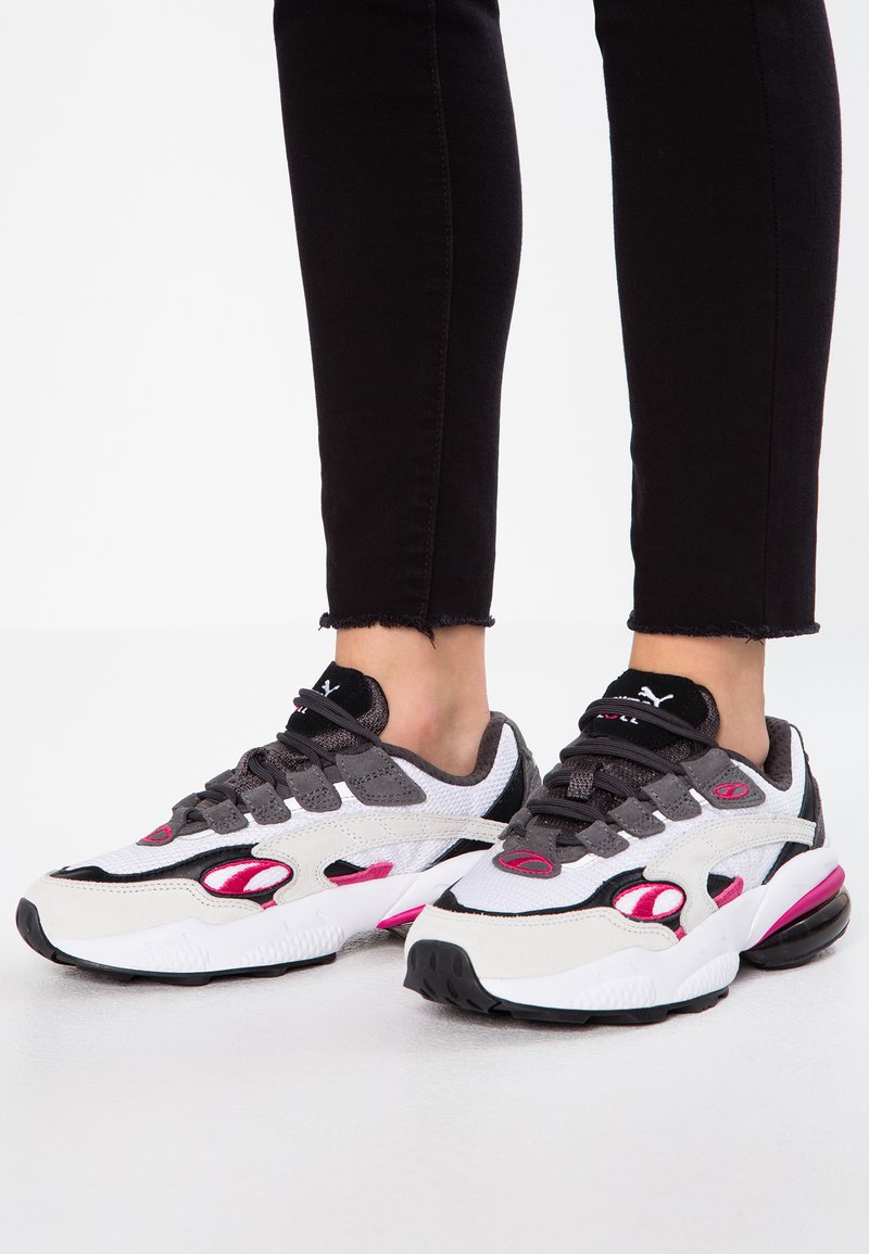 Sneakers sportive caratterizzati da una combinazione di materiali bianchi, grigi e rosa. Forma ampia con rete testurizzata, suola ammortizzata e chiusura con lacci.