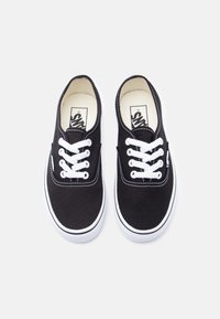 Μαύρα πάνινα παπούτσια με λευκά κορδόνια, καουτσούκ σόλες και αντίθετες ραφές. Κλασικός σχεδιασμός με χαμηλό προφίλ.