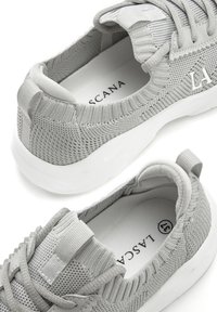 Gray knit sneakers with a soft texture, white rubber sole, and looped heel tab. Features laced front and logo detail on the side.