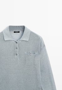 Polo a maniche lunghe in maglia grigio chiaro con colletto a coste, patta con tre bottoni e una piccola tasca con bottone sul petto sinistro.