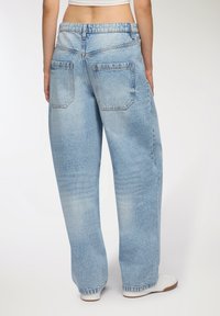 Jasnoniebieskie dżinsy o szerokich nogawkach z luźnym krojem, z dwoma tylnymi kieszeniami i miękkim, teksturowanym materiałem.