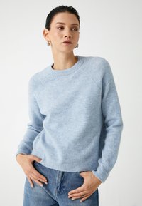 Helles blaues Sweatshirt mit Rundhalsausschnitt, gerippten Bündchen und Saum. Hergestellt aus weichem, strukturiertem Stoff, mit Raglanärmeln und einer lockeren Passform.