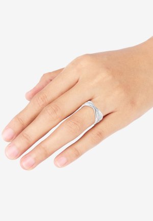 Silberner Ring mit ineinander verschlungenen Bändern mit glatten und strukturierten Oberflächen, präsentiert auf einer Hand mit natürlichen Nägeln.
