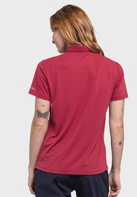 Rotes Poloshirt mit Kragen, kurzen Ärmeln und lockerem Schnitt. Hergestellt aus einem leichten Material mit dezenten Stichdetails.
