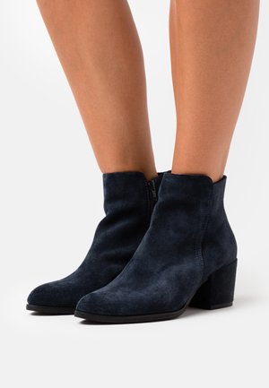 Marineblaue Wildleder-Stiefeletten mit einem Blockabsatz, die über eine glatte Textur, einen seitlichen Reißverschluss und ein rundes Fußbett verfügen.