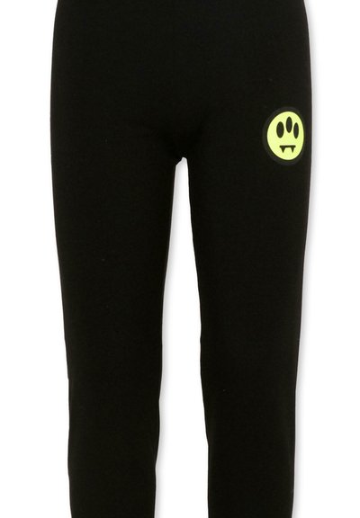 Pantaloni neri con una piccola toppa circolare giallo-verde che presenta tre occhi ovali e zanne sulla coscia superiore.