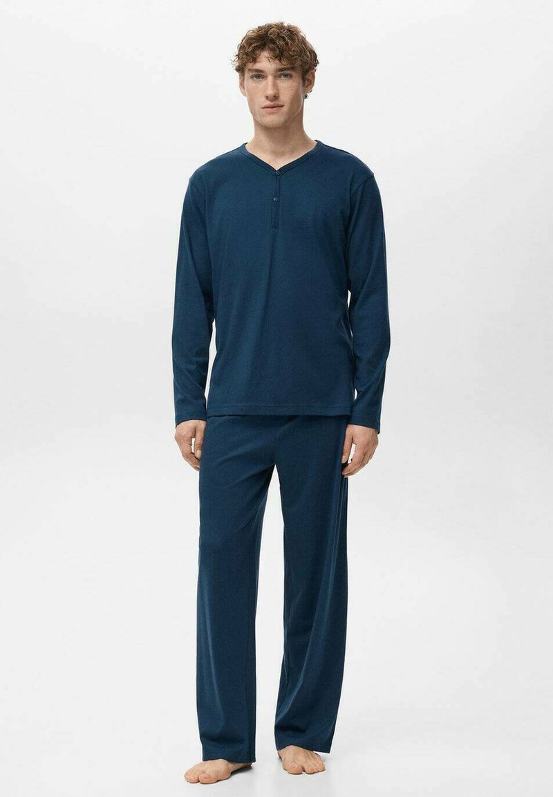 Conjunto de pijama azul marino hecho de tela suave y elástica; camiseta de manga larga con cuello en V y detalle de botones, combinada con pantalones holgados.