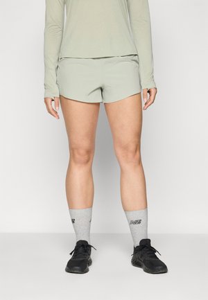 Light green athletic shorts with a smooth texture, paired with gray socks featuring printed accents and black running shoes.