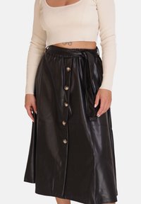 Schwarzer Rock aus Kunstleder in Midi-Länge, mit durchgehender Knopfleiste vorne, tailliertem Gürtel und glatter, glänzender Oberfläche.