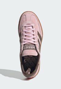 Sapatilha de camurça rosa com detalhes em pele castanha, bico arredondado, atacadores planos e sola de borracha texturizada. Apresenta uma marca no atalho e na palmilha.