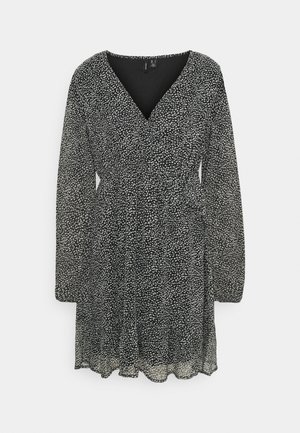 Zwarte jurk met een wikkelontwerp, v-hals, lange mouwen en een geplooide rok. De stof heeft een gespoten wit patroon door het geheel.