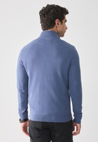 Blåstrikket genser med høy krage, lange ermer og ribbestrikket nederkant. Smooth tekstur og tettsittende design for et moderne utseende.