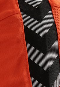 De oranje stof aan de linkerkant contrasteert met de zwart-witte stof met zigzagpatroon aan de rechterkant, die textuur heeft in de horizontale lijnen.