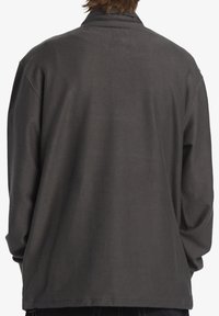 Gray textured jacket with long sleeves, a relaxed fit, and a fold-down collar. Features subtle geometric patterns throughout.