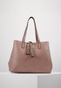 Sac cabas en cuir mauve doux, doté de deux longues anses, d'une fermeture par cordon avec pompons, et d'une surface lisse, sans ornement.