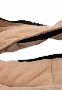 Veste en polaire beige clair avec une texture douce, fermeture éclair noire et accents en Velcro, dotée d'une doublure intérieure lisse et d'un design matelassé.