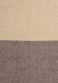 Textiel met een zachte, geweven textuur en een tweekleurig ontwerp: lichtbeige bovenaan en donkerbruin onderaan, met diagonale lijnen.