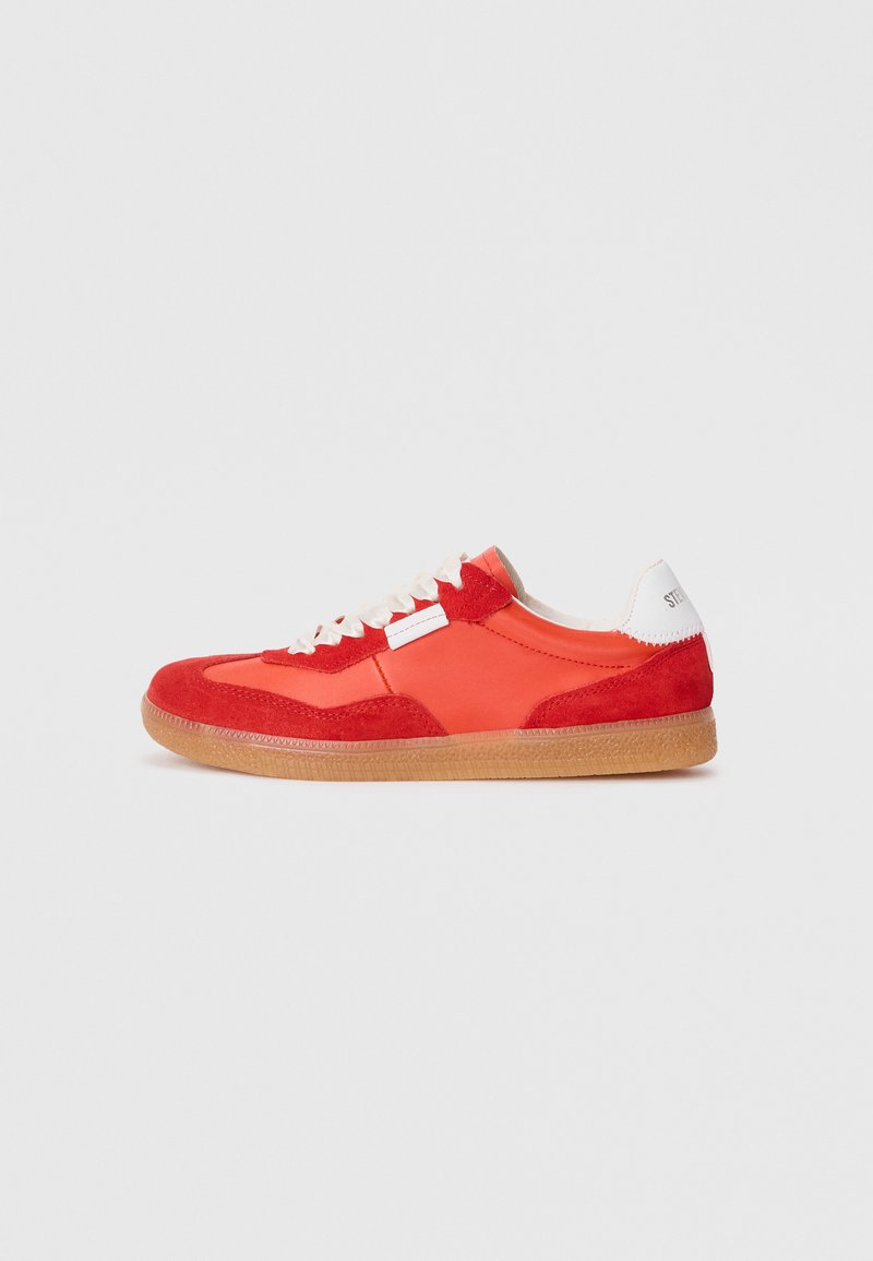 Red and orange low-top sneaker with beige laces, gum sole, and white heel tab on plain light gray background.