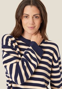 Gestreifter Pullover in Marineblau und Creme, mit gerippter Textur, rundem Ausschnitt und langen Ärmeln mit breiten Bündchen.