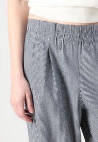 Blue and white striped trousers with a pleated front, made of a lightweight fabric. The waistband is flat, and the texture is smooth.